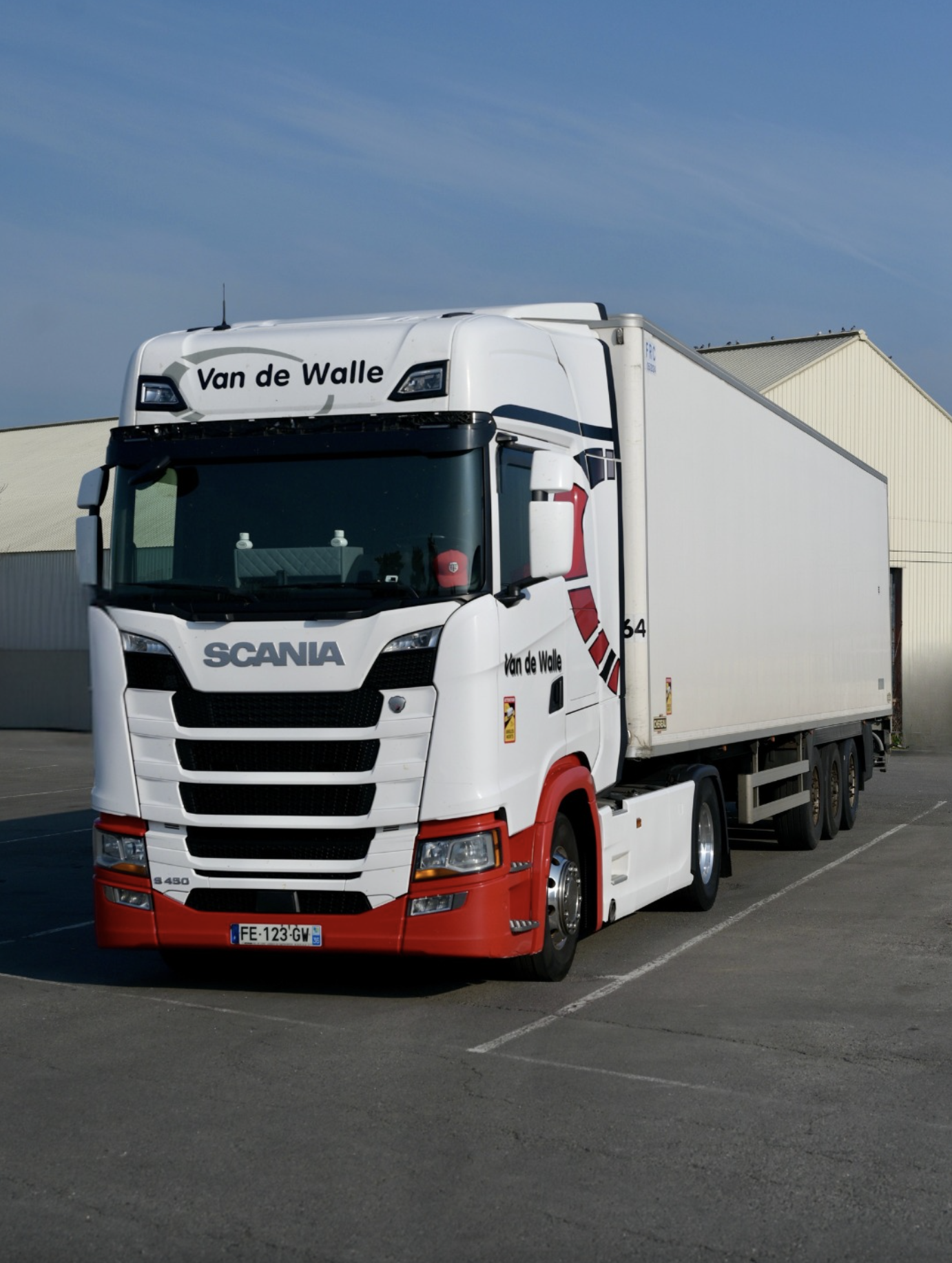 Camion poids lourd Scania blanc et rouge aux couleurs de Van de Walle stationné sur un site logistique.