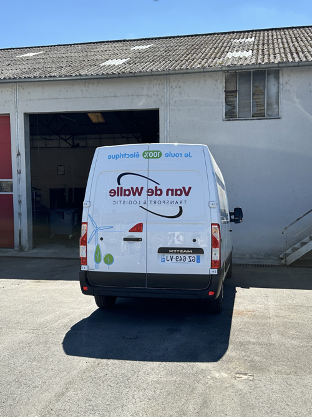 Fourgon électrique Van de Walle stationné devant un bâtiment logistique, illustrant les engagements RSE et la mobilité électrique de l’entreprise.